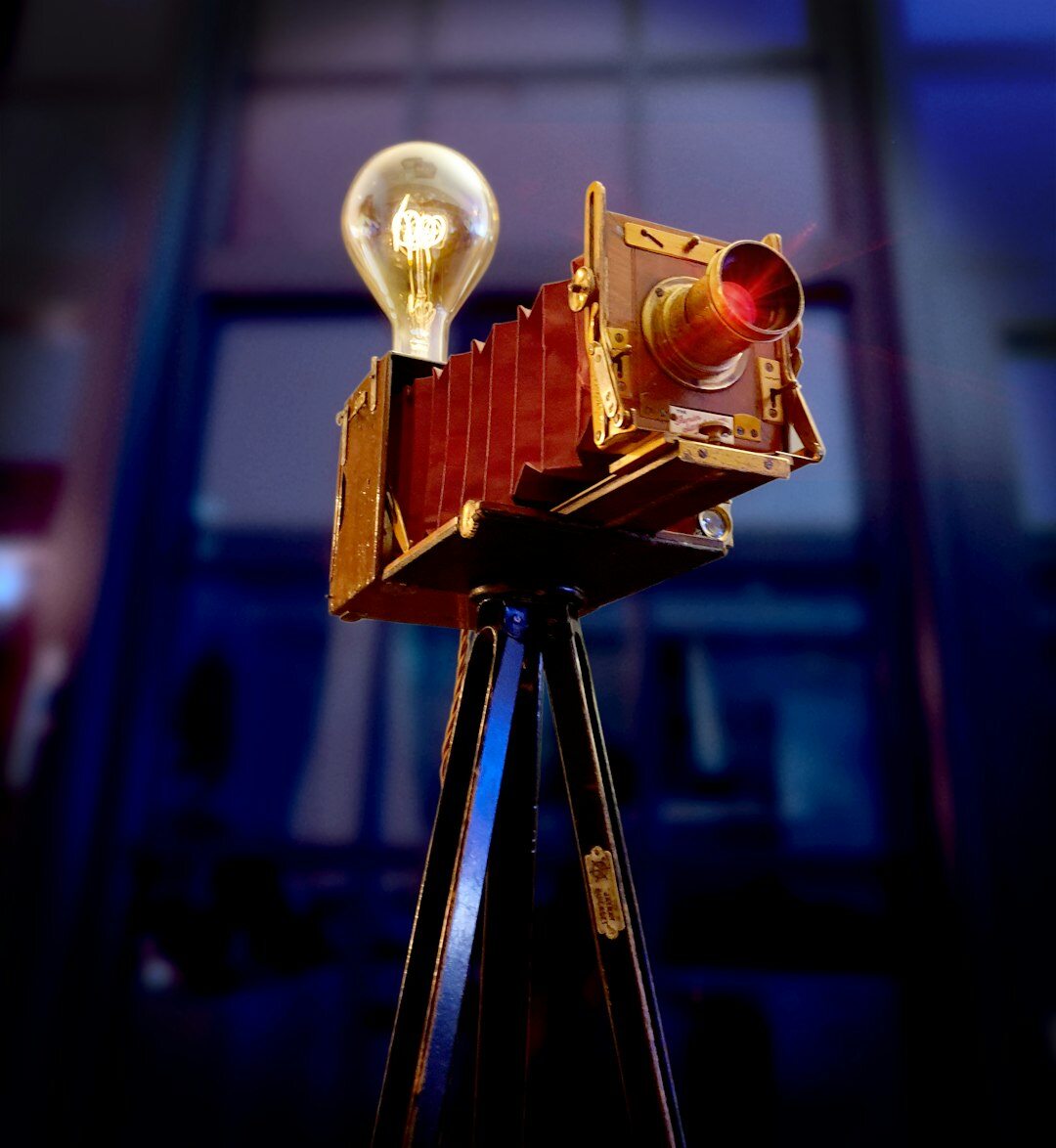 Vintage-Fernsehkamera auf einem Studiostativ mit warmen Studioleuchten im Hintergrund